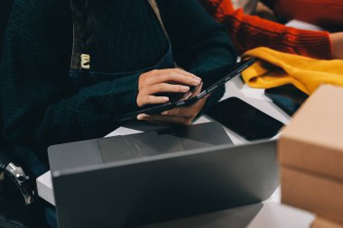 Küçük işletmeler kurma portresi KOBİ sahipleri ve iki Asyalı kadın online siparişleri kontrol ediyor. Ev işlerinde çalışan kutucuklarla çalışan ürünleri satıyorlar.