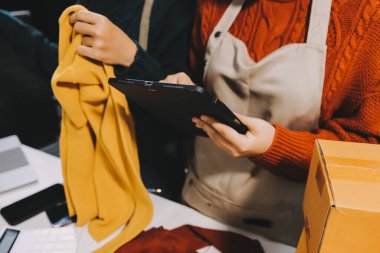 Küçük işletmeler kurma portresi KOBİ sahipleri ve iki Asyalı kadın online siparişleri kontrol ediyor. Ev işlerinde çalışan kutucuklarla çalışan ürünleri satıyorlar.