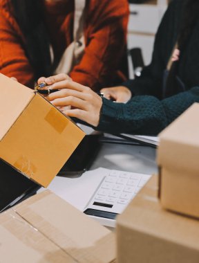 Küçük işletmeler kurma portresi KOBİ sahipleri ve iki Asyalı kadın online siparişleri kontrol ediyor. Ev işlerinde çalışan kutucuklarla çalışan ürünleri satıyorlar.