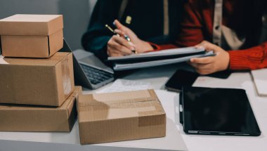 Küçük işletmeler kurma portresi KOBİ sahipleri ve iki Asyalı kadın online siparişleri kontrol ediyor. Ev işlerinde çalışan kutucuklarla çalışan ürünleri satıyorlar.