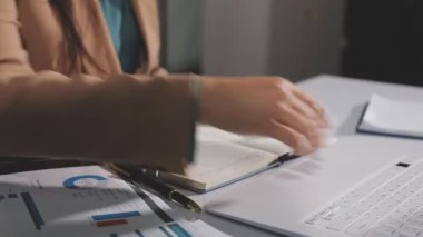 İş kadını iş yerinde deftere yazı yazıyor.