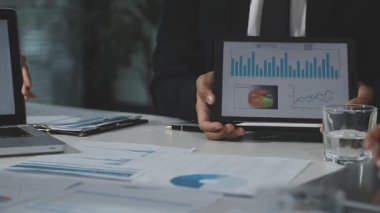 İş adamları mali istatistikleri tartışıyor ve ofiste çizelgeleri tartışıyorlar.