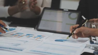 İş ekibi bilgisayarda çalışıyor ve ofiste mali verileri tartışıyor.