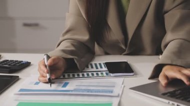 Ofiste tablet ve hesap makinesi kullanan bir iş kadını.