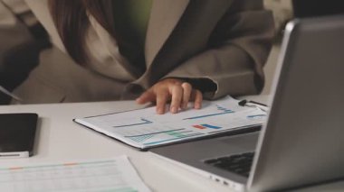 Genç iş kadını ofisinde finansal verileri ve dizüstü bilgisayarı analiz ediyor. iş kavramı.