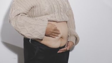 Gri arka planda midesi olan genç bir adam..