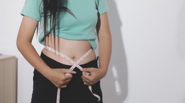 Belini ölçen genç bir kadın.