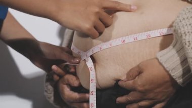 Şişman bir kadının belini ölçen kadın.