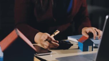 Ofiste hesap makinesi ve dizüstü bilgisayar kullanan iş kadını eli, emlak kavramı.