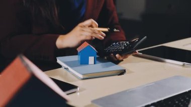 Kadın elinde hesap makinesi ve kalemle evde.