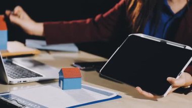 Emlakçı ev modeli ve tablet bilgisayarı ev almak için gösteriyor.