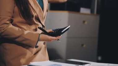 Ofisinde hesap makinesi olan bir iş kadını.