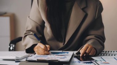 Genç iş kadını ofiste kağıda yazı yazıyor.