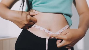 Karnını bantla ölçen bir kadın.