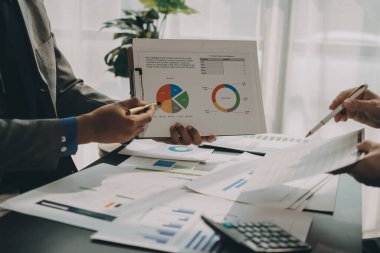 Muhasebe şirketi kazançlı nakit akışı için finansman ve vergilendirme planlaması, ofiste çalışan denetçi ve muhasebeci ekibi, mali verileri ve muhasebe kayıtlarını hesap makinesiyle analiz eder.