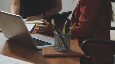 Genç iş kadını modern ofiste çalışıyor. Masasında dizüstü bilgisayar ve not defteriyle oturuyor.