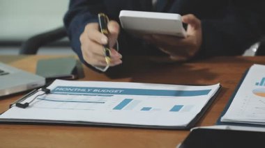 Kapat. Ofiste çalışan kalem ve hesap makinesi olan bir iş adamı.