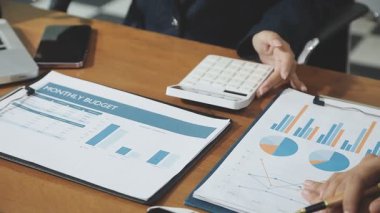 İşletme ekibi, mali rapor ve dizüstü bilgisayarla ofiste çalışıyor.