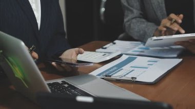 Modern ofiste dizüstü bilgisayar üzerinde çalışan ve finansal verileri tartışan iş adamları