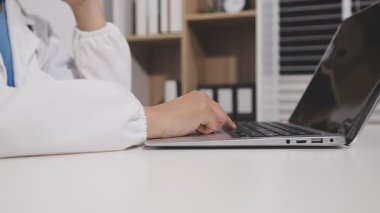 Ofisteki dizüstü bilgisayarda klavyede yazan doktor.