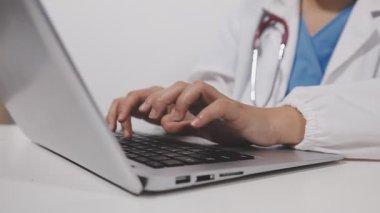 Kadın doktor bilgisayar kullanıyor ve dizüstü bilgisayarda yazıyor.