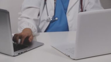 Evindeki ofisinde dizüstü bilgisayarı olan genç bir doktor, teletıp konsepti, yakın görüş.