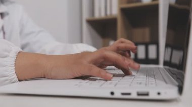 Kadın doktor ofiste dizüstü bilgisayar kullanıyor.