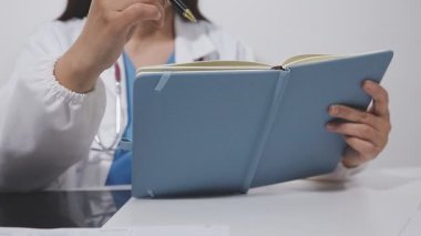 Kadın doktor deftere yazıyor.