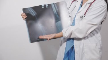 Gri arka planda röntgen çeken genç bir doktor.