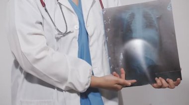 Elinde steteskop olan beyaz röntgenli bir doktor, tıbbi bir radyologun arka planında, x -