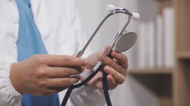 Doktor steteskop tutuyor ve kameraya bakıyor.