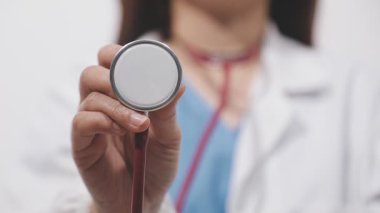 Kadın doktor arka planda steteskop tutuyor.