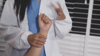 Doktor hastanın bileğini kontrol ediyor.