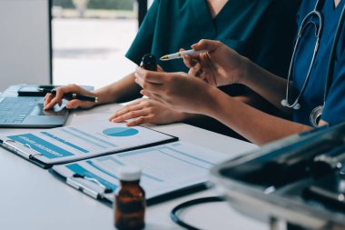 Medical team meeting analyzing blood test results in hospital laboratory. Doctors and scientists in lab coats are having a discussion about blood test result, holding test tubes and taking notes.