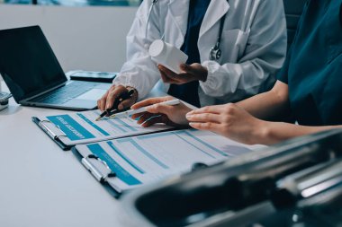 Medical team meeting analyzing blood test results in hospital laboratory. Doctors and scientists in lab coats are having a discussion about blood test result, holding test tubes and taking notes.