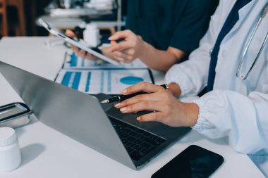 Medical team meeting analyzing blood test results in hospital laboratory. Doctors and scientists in lab coats are having a discussion about blood test result, holding test tubes and taking notes.
