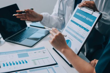 Medical team meeting analyzing blood test results in hospital laboratory. Doctors and scientists in lab coats are having a discussion about blood test result, holding test tubes and taking notes.