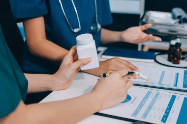 Medical team meeting analyzing blood test results in hospital laboratory. Doctors and scientists in lab coats are having a discussion about blood test result, holding test tubes and taking notes.