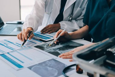 Medical team meeting analyzing blood test results in hospital laboratory. Doctors and scientists in lab coats are having a discussion about blood test result, holding test tubes and taking notes.