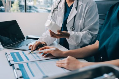 Medical team meeting analyzing blood test results in hospital laboratory. Doctors and scientists in lab coats are having a discussion about blood test result, holding test tubes and taking notes.