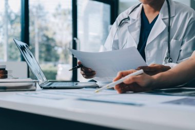 Medical team meeting analyzing blood test results in hospital laboratory. Doctors and scientists in lab coats are having a discussion about blood test result, holding test tubes and taking notes.