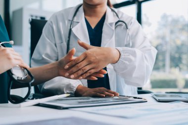 Medical team meeting analyzing blood test results in hospital laboratory. Doctors and scientists in lab coats are having a discussion about blood test result, holding test tubes and taking notes.