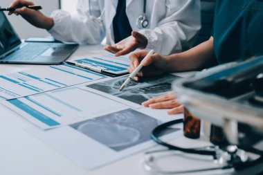Medical team meeting analyzing blood test results in hospital laboratory. Doctors and scientists in lab coats are having a discussion about blood test result, holding test tubes and taking notes.