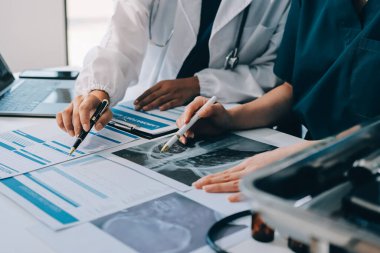 Medical team meeting analyzing blood test results in hospital laboratory. Doctors and scientists in lab coats are having a discussion about blood test result, holding test tubes and taking notes.
