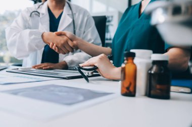 Medical team meeting analyzing blood test results in hospital laboratory. Doctors and scientists in lab coats are having a discussion about blood test result, holding test tubes and taking notes.