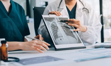 Medical team meeting analyzing blood test results in hospital laboratory. Doctors and scientists in lab coats are having a discussion about blood test result, holding test tubes and taking notes.