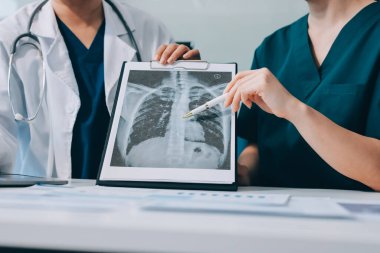 Medical team meeting analyzing blood test results in hospital laboratory. Doctors and scientists in lab coats are having a discussion about blood test result, holding test tubes and taking notes.