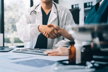 Medical team meeting analyzing blood test results in hospital laboratory. Doctors and scientists in lab coats are having a discussion about blood test result, holding test tubes and taking notes.