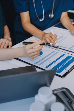 Medical team meeting analyzing blood test results in hospital laboratory. Doctors and scientists in lab coats are having a discussion about blood test result, holding test tubes and taking notes.