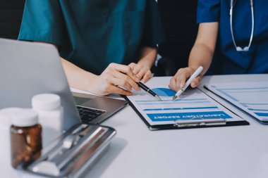 Medical team meeting analyzing blood test results in hospital laboratory. Doctors and scientists in lab coats are having a discussion about blood test result, holding test tubes and taking notes.